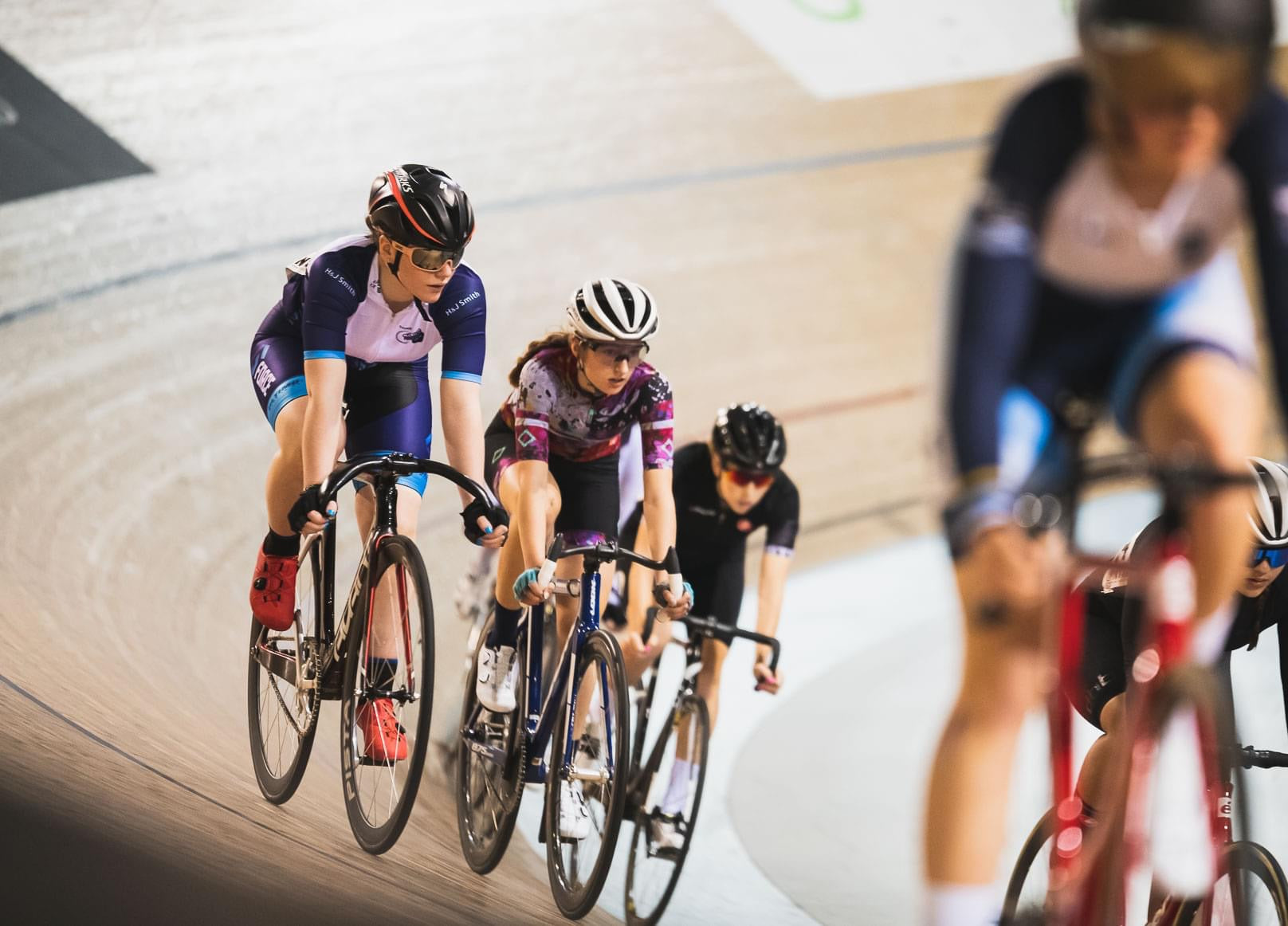 Junior track cyclist racing on an indoor wooden velodrome 