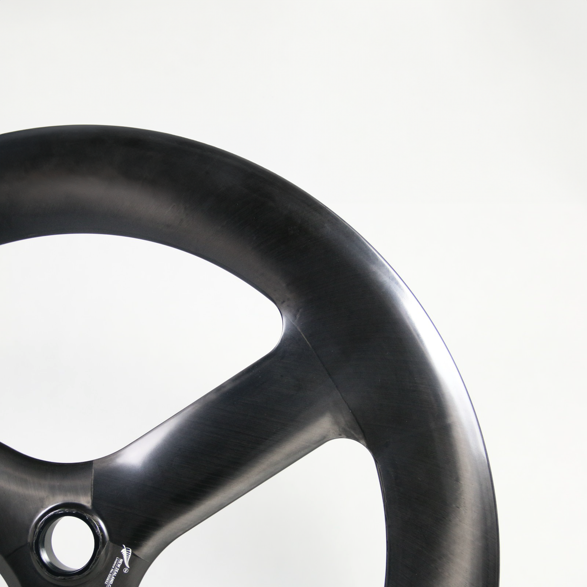 Close-up of a black carbon fiber bike wheel rim on a light gray background.